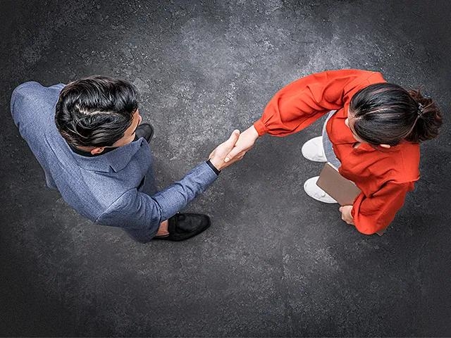 Zwei Personen reichen sich zur Begrüßung die Hand.