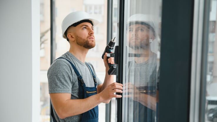 Ein Handwerker tauscht ein Fenster aus.