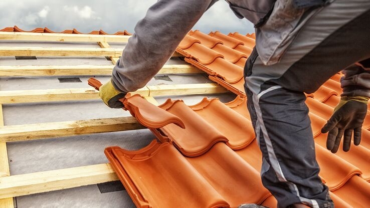 Ein Handwerker setzt neue Dachziegel.